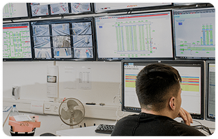 A man is seated in front of multiple computer screens