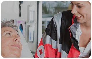 A female medical professional looks down at another woman in a hospital bed