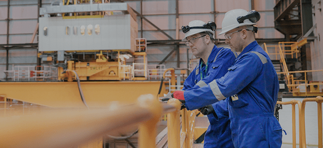 Two men in work uniforms standing in a factory