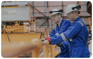 Two men in work uniforms standing in a factory
