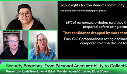 Two cybersecurity professionals reviewing data at a conference, representing the shift from personal accountability to collective action in preventing security breaches