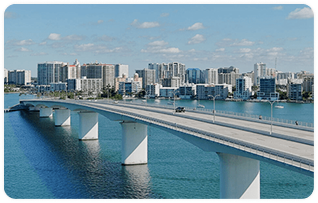 A bridge running across a body of water with a cityscape in the background