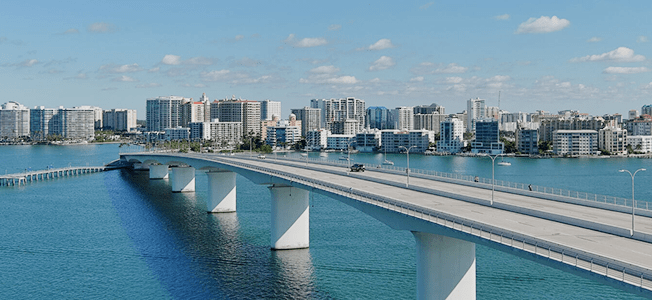 A bridge running across a body of water with a cityscape in the background