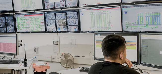 A man is seated in front of multiple computer screens
