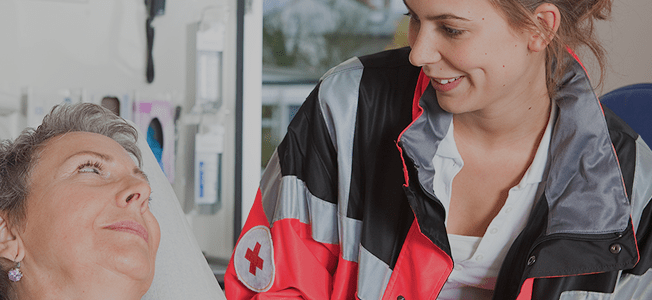 A female medical professional looks down at another woman in a hospital bed